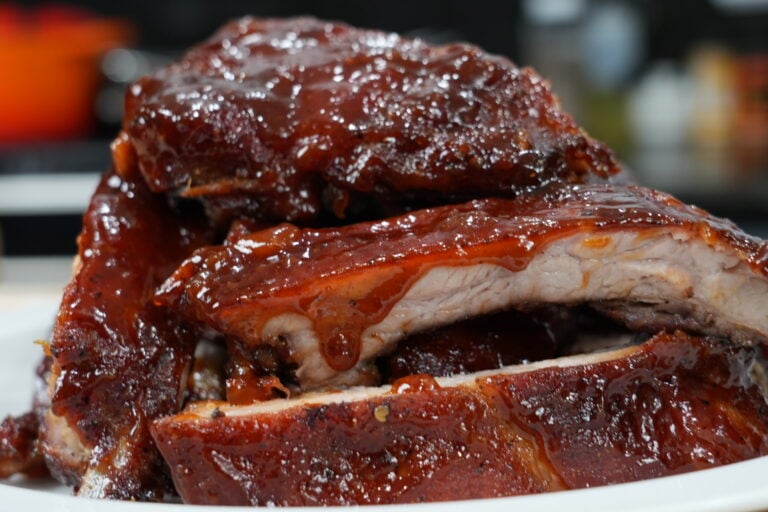 a pile of oven baked bbq ribs with sauce