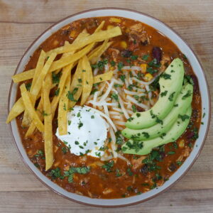 Chicken Tortilla Soup photo garnished with avocado, sour cream, cheese, and homemade tortilla chips