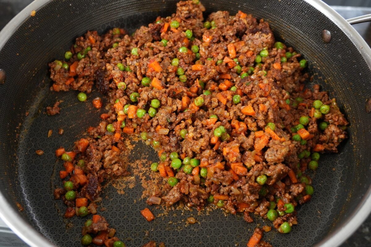 Shepherd's pie assembled in a baking dish topped with mashed potatoes and shredded cheese before baking