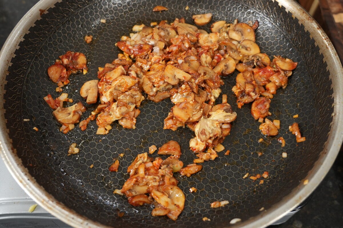 Rich cognac mushroom pan sauce reducing in a stainless steel skillet