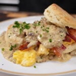 Homemade biscuits and gravy on a plate, split open and smothered in creamy sausage gravy