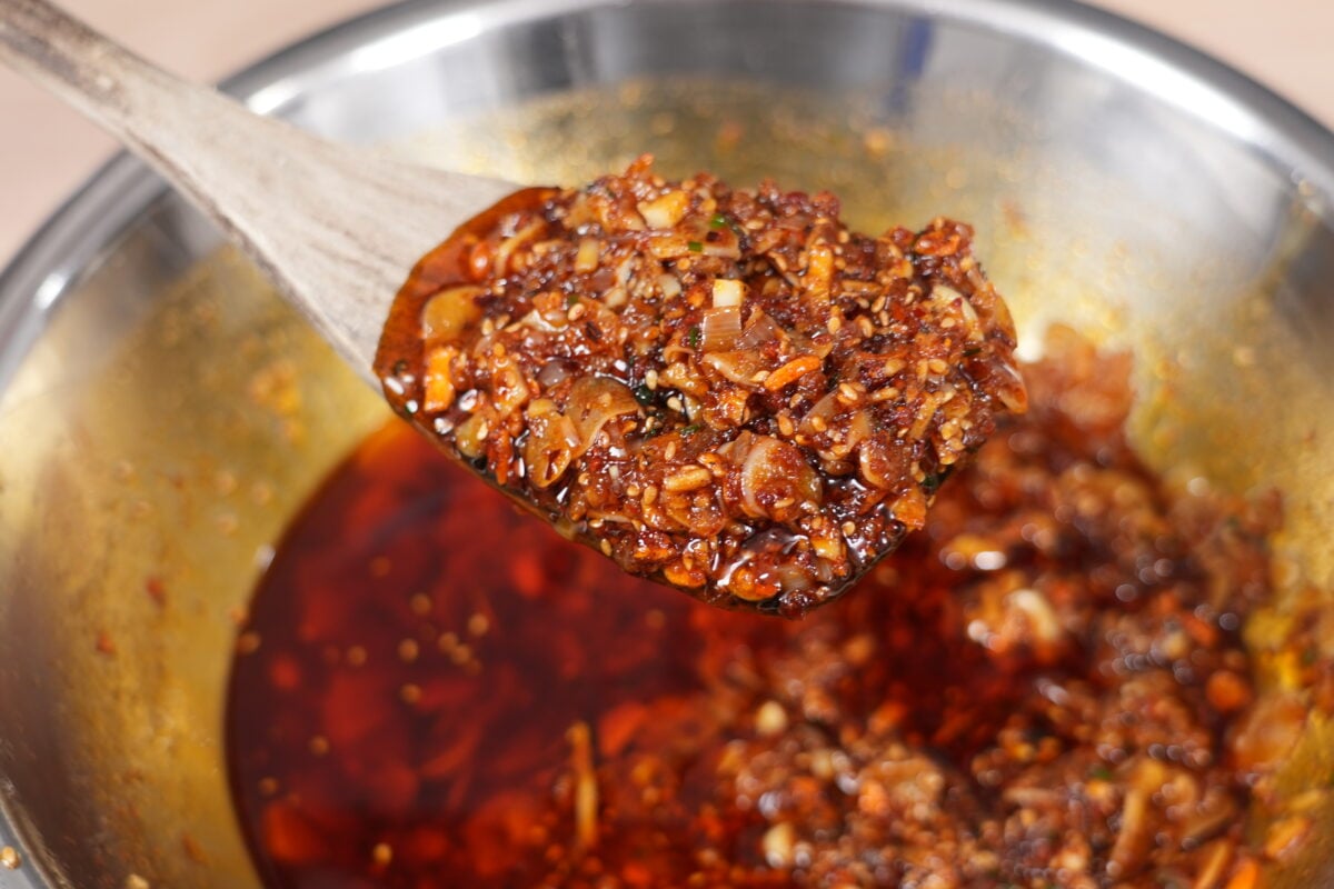 Crispy chili crisp condiment spooned over noodles