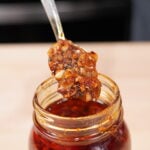 Homemade chili garlic crunch in a glass jar with a spoon