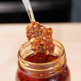 Homemade chili garlic crunch in a glass jar with a spoon