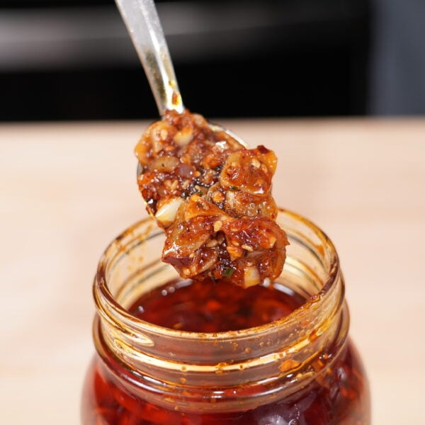 Homemade chili garlic crunch in a glass jar with a spoon