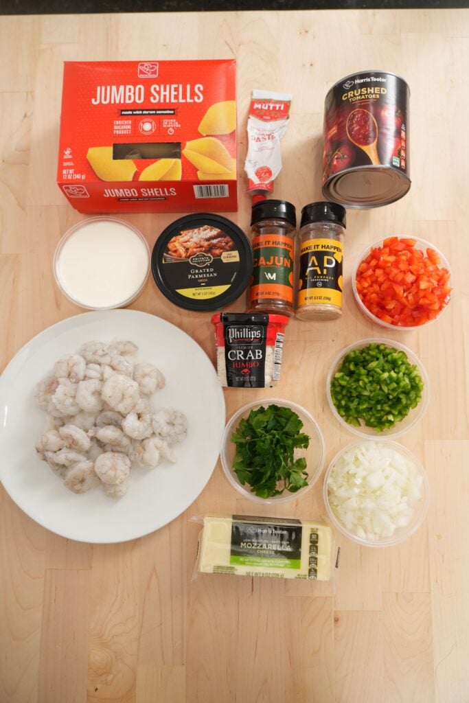 Ingredient flat-lay: jumbo pasta, shrimp, lump crab, bell peppers, onion, and parmesan