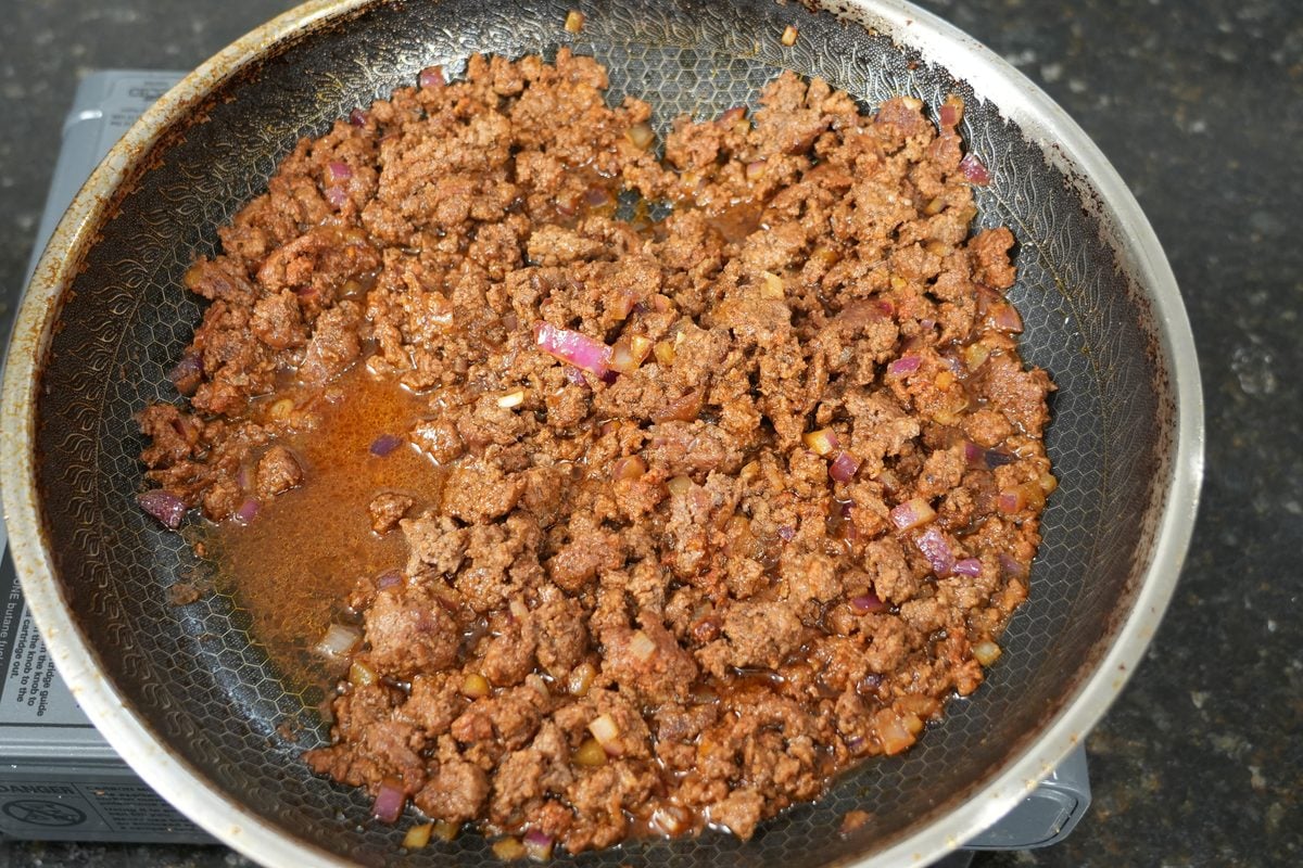 Seasoned ground beef browning in a skillet for beef nachos