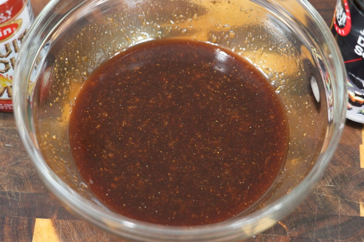 Whisked lo mein sauce in a glass bowl, dark brown and glossy
