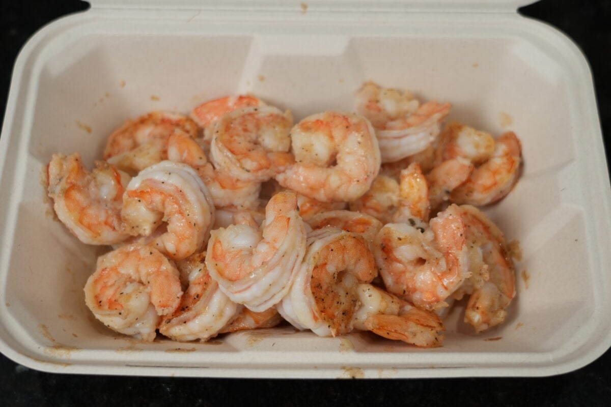 Peeled raw shrimp seasoned with AP Seasoning in a white container