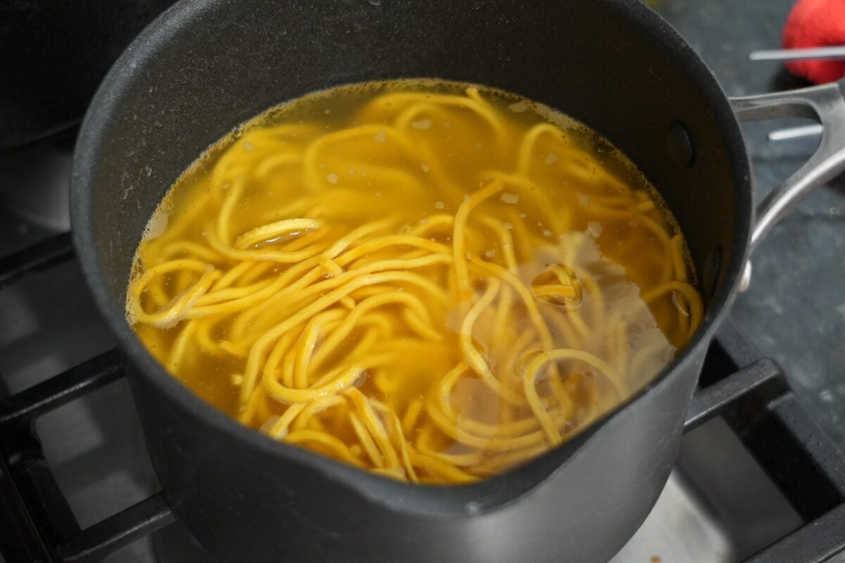 Fresh egg noodles boiling in a pot of water on the stove