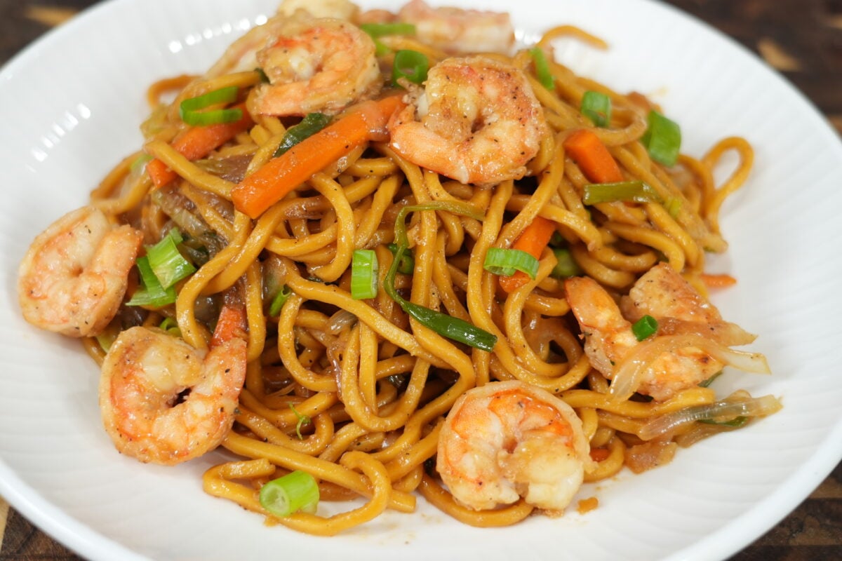 Close-up of plated lo mein with shrimp, carrots and green onions