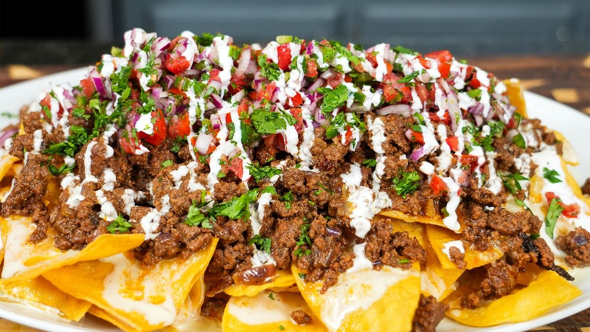 A platter of loaded beef nachos with homemade queso, seasoned ground beef, and pico de gallo