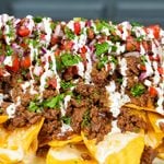 A platter of loaded beef nachos with homemade queso, seasoned ground beef, and pico de gallo