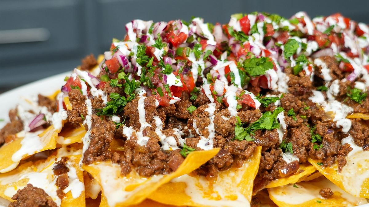 Loaded beef nachos topped with seasoned ground beef, fresh pico de gallo, and a crema drizzle