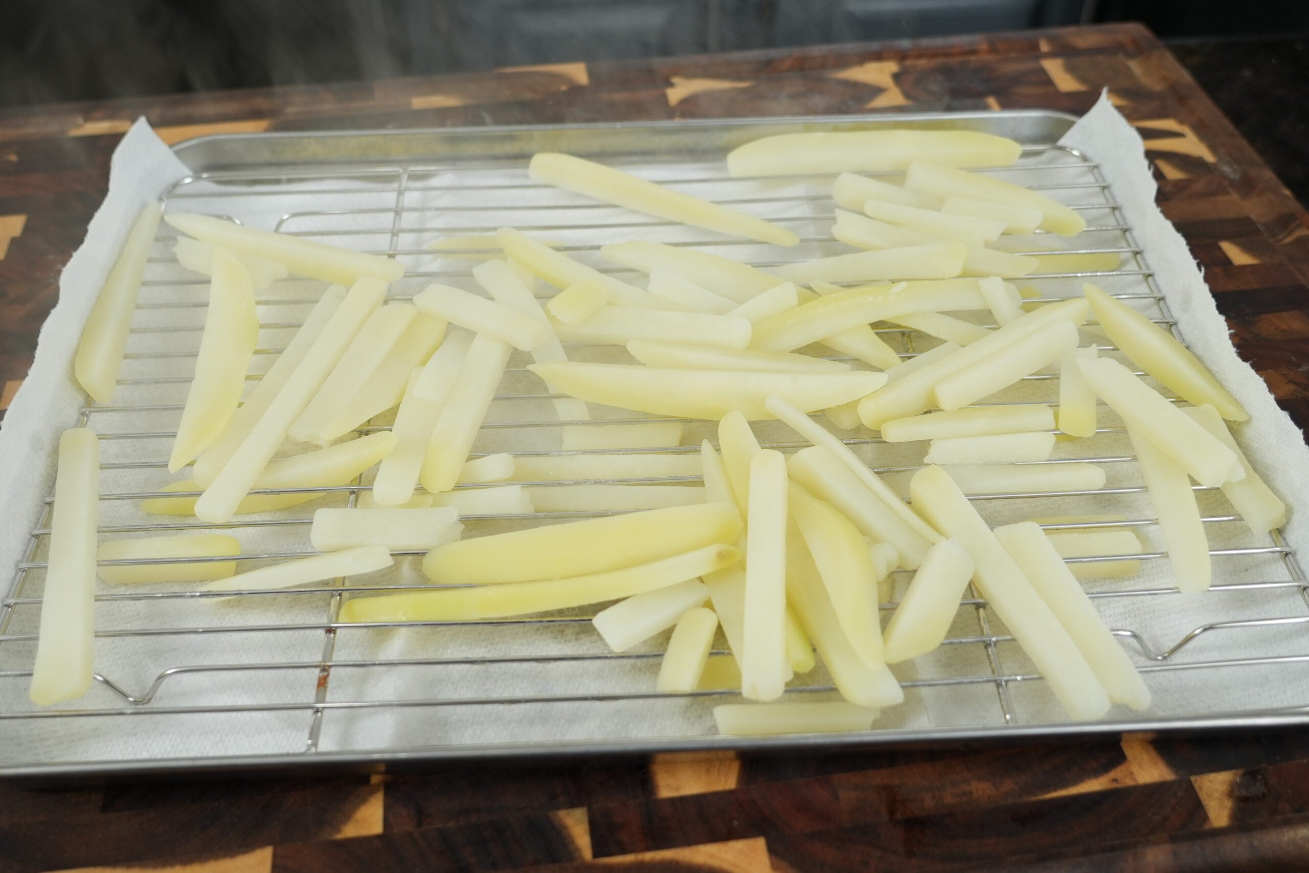 Parboiled potato chips steam-drying on a wire rack