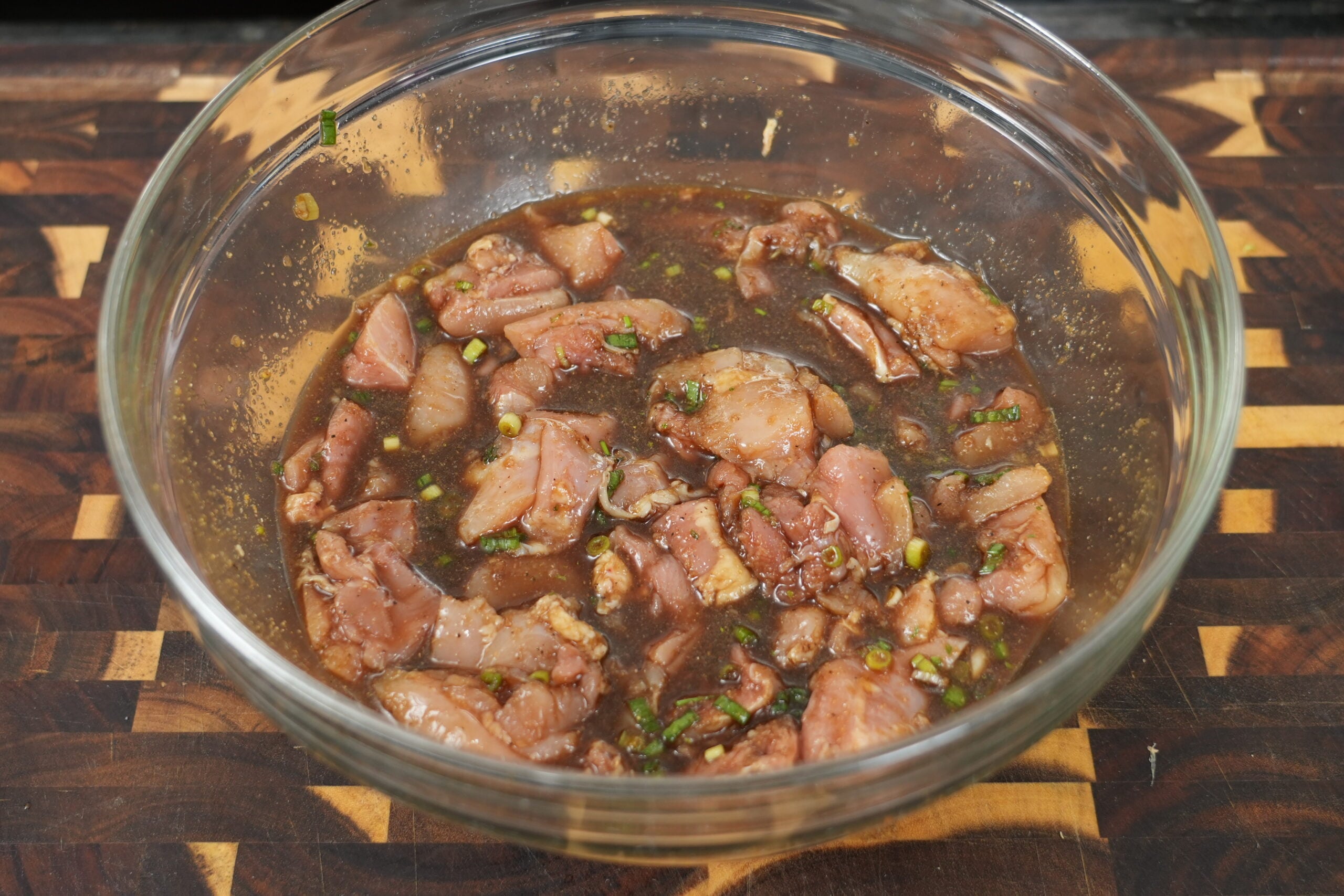 Bite-size chicken thighs marinating in bourbon chicken sauce