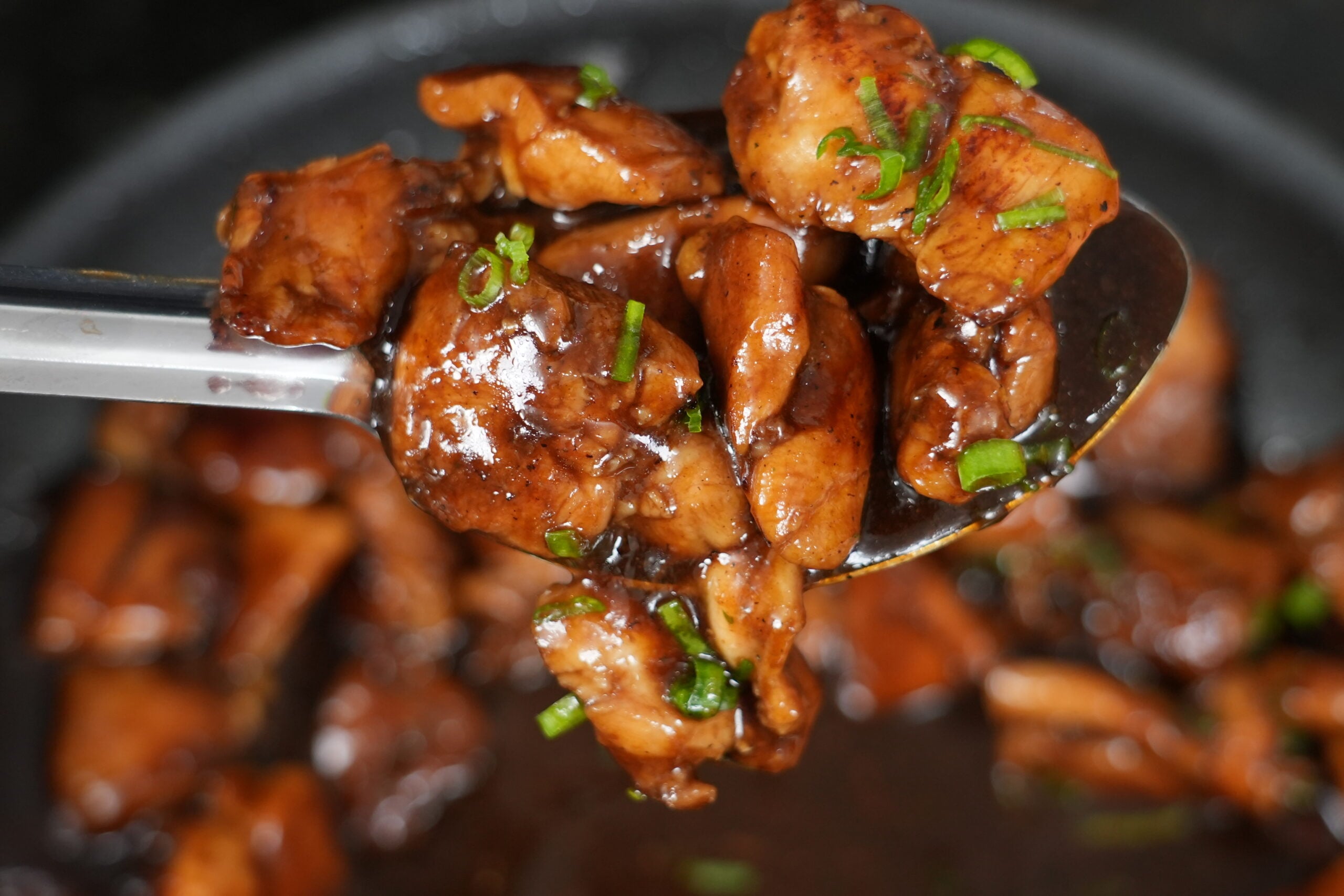Glossy finished bourbon chicken on a serving spoon