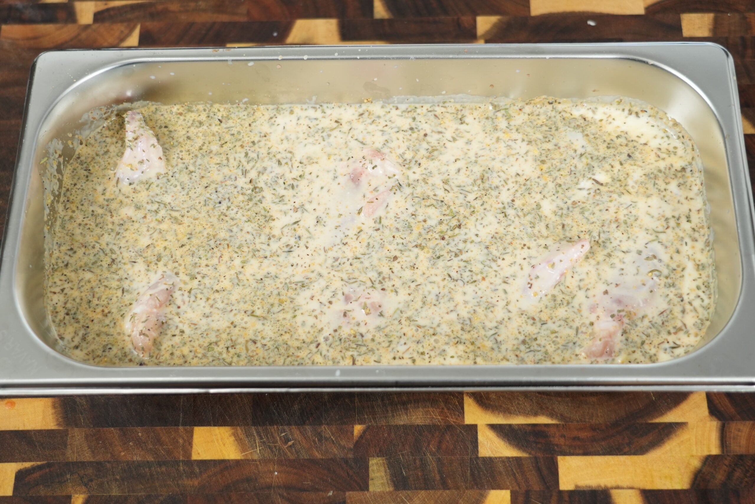 Whole chicken wings submerged in seasoned buttermilk brine