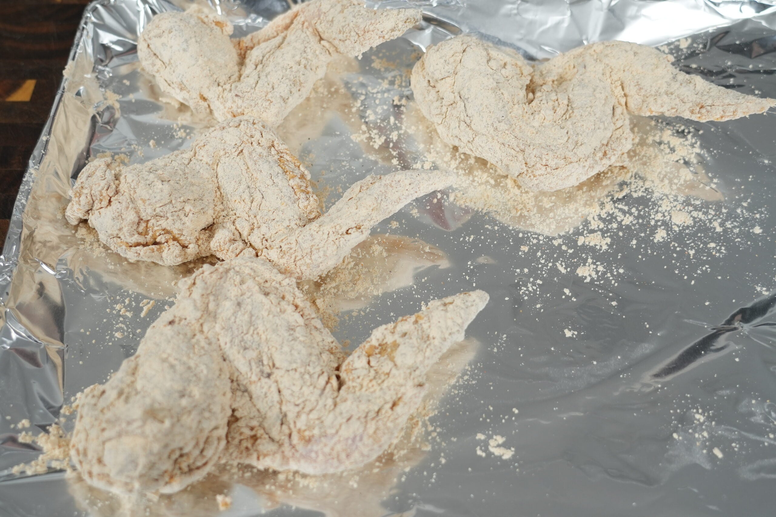 Whole chicken wings covered in seasoned flour and ready to fry