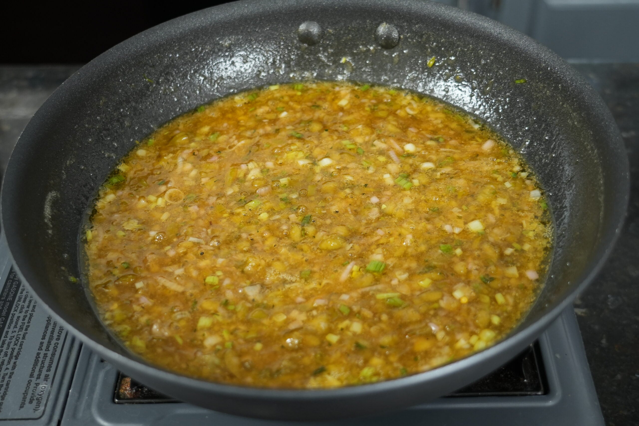 Jalapeño honey butter simmering with shallot and scallions in a skillet