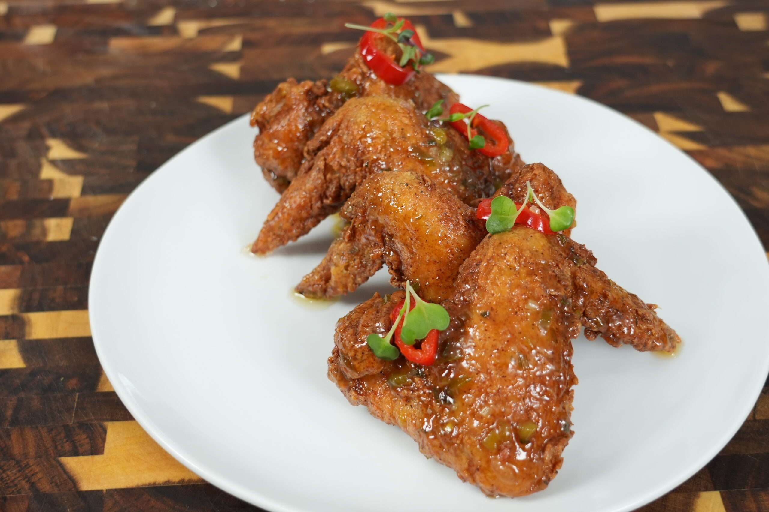 Crispy fried chicken wings coated with jalapeño honey glaze on a white plate