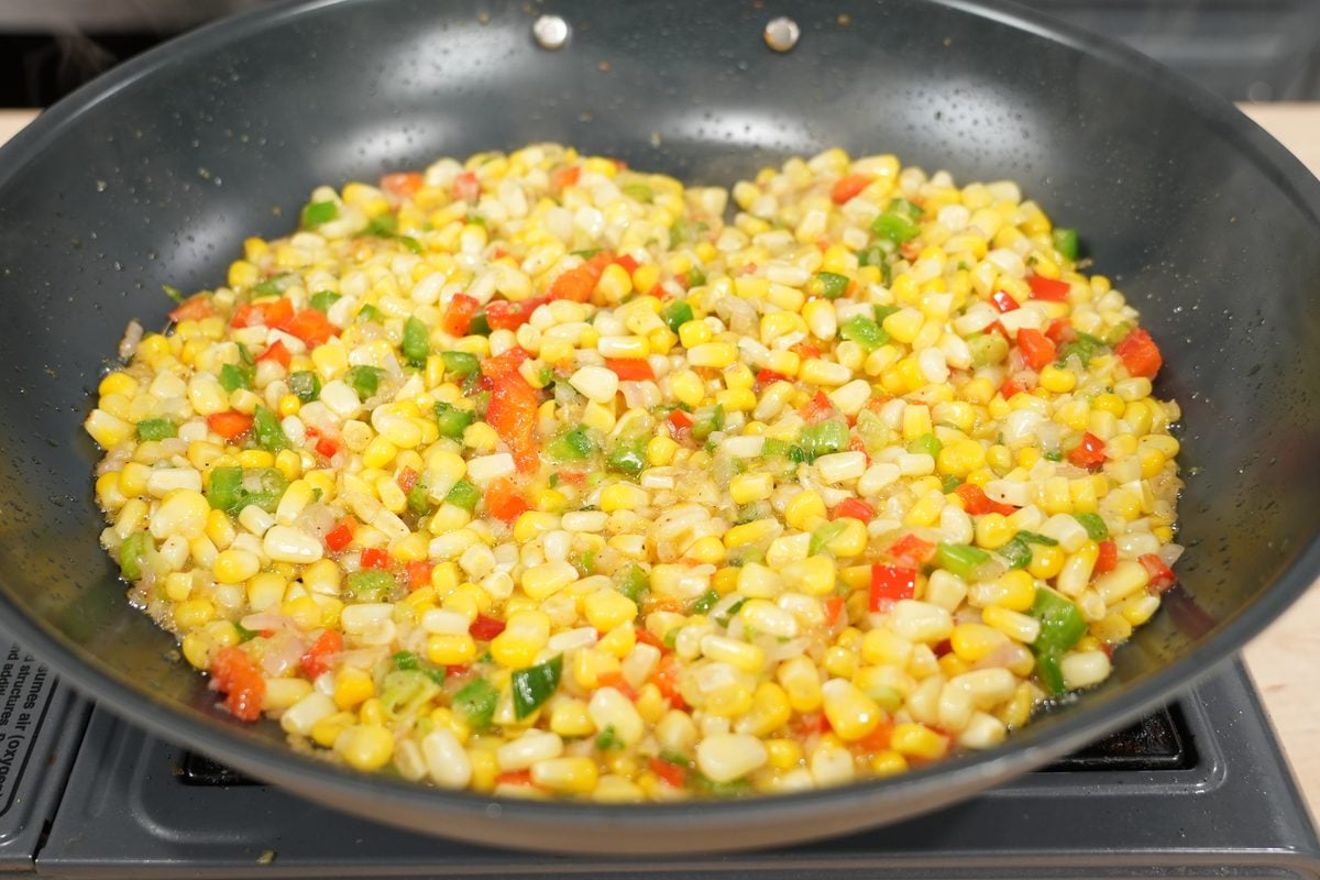 Fresh corn kernels sautéed with red and green peppers for Cajun salmon