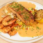 Cajun salmon with seared shrimp, corn, loaded red potatoes, and cream sauce
