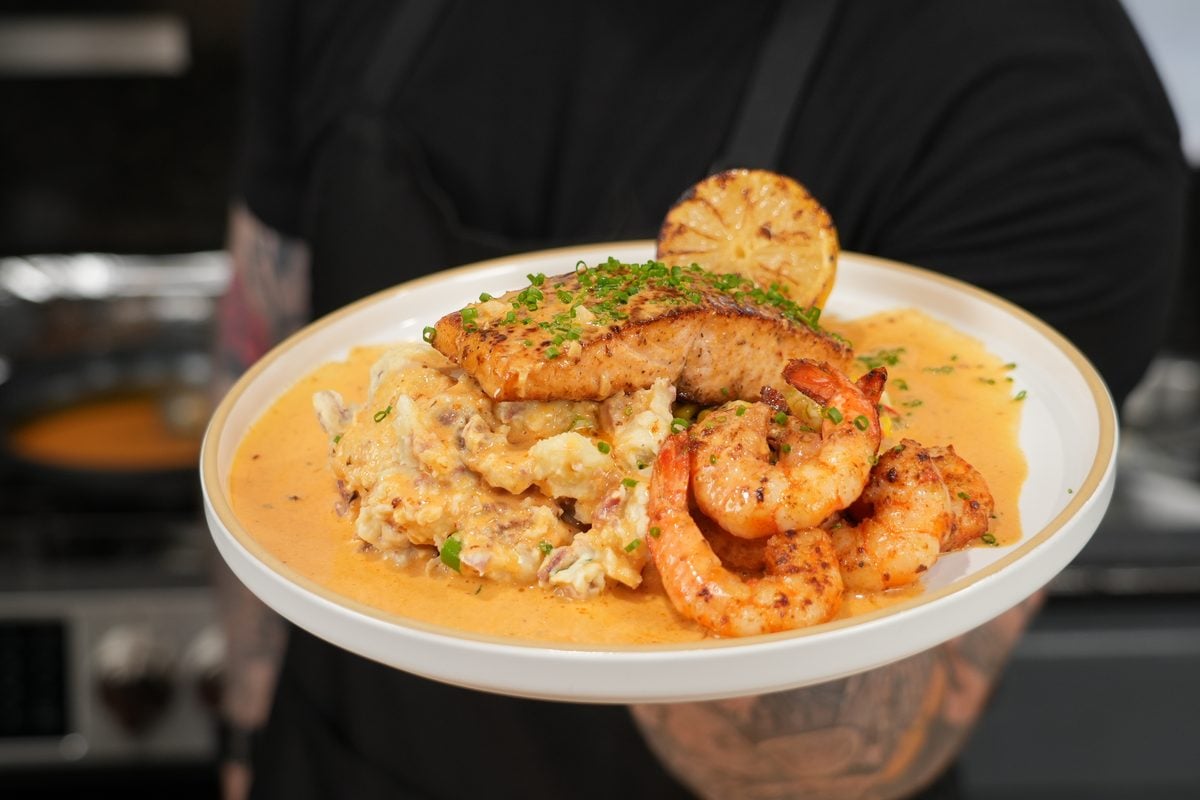 Cajun salmon and seared shrimp plated with loaded potatoes, corn, and creamy sauce