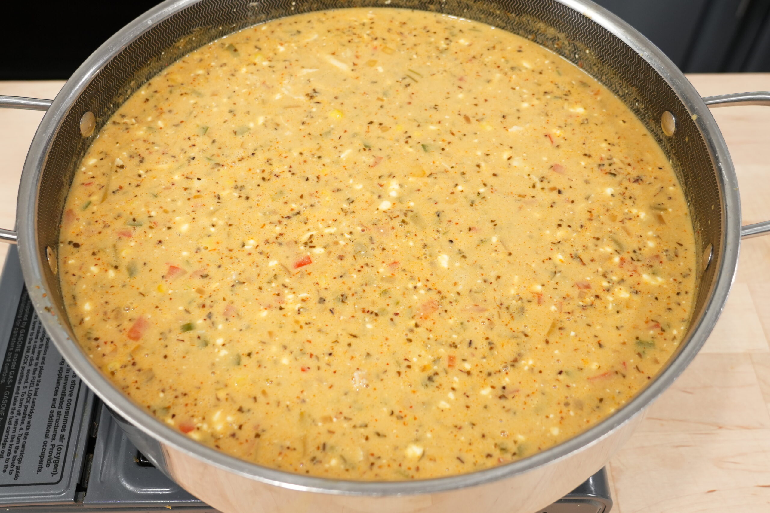 Pot of creamy white chicken chili simmering with chicken, white beans, corn, and peppers