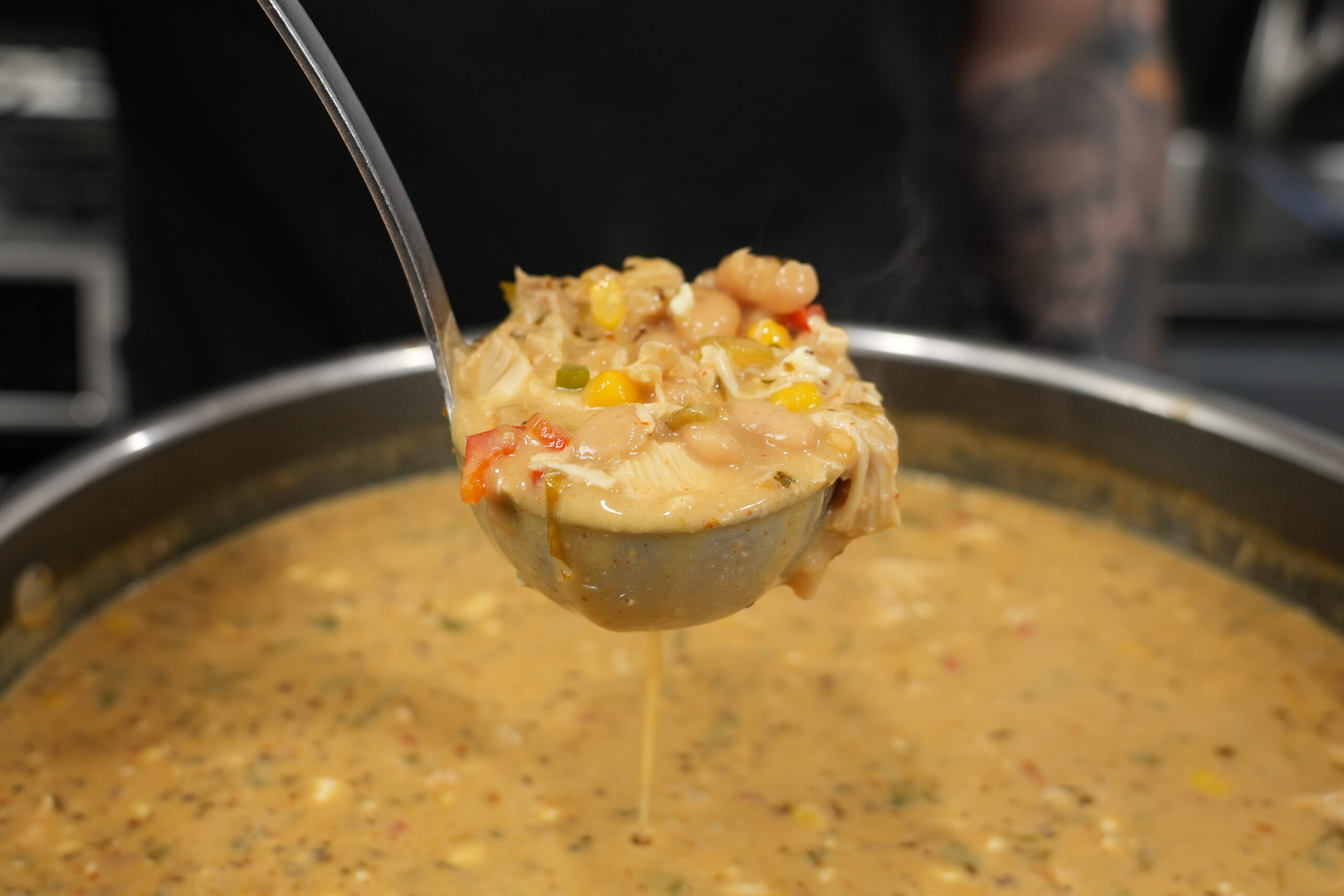 Ladle of creamy white chicken chili with shredded chicken, white beans, and corn