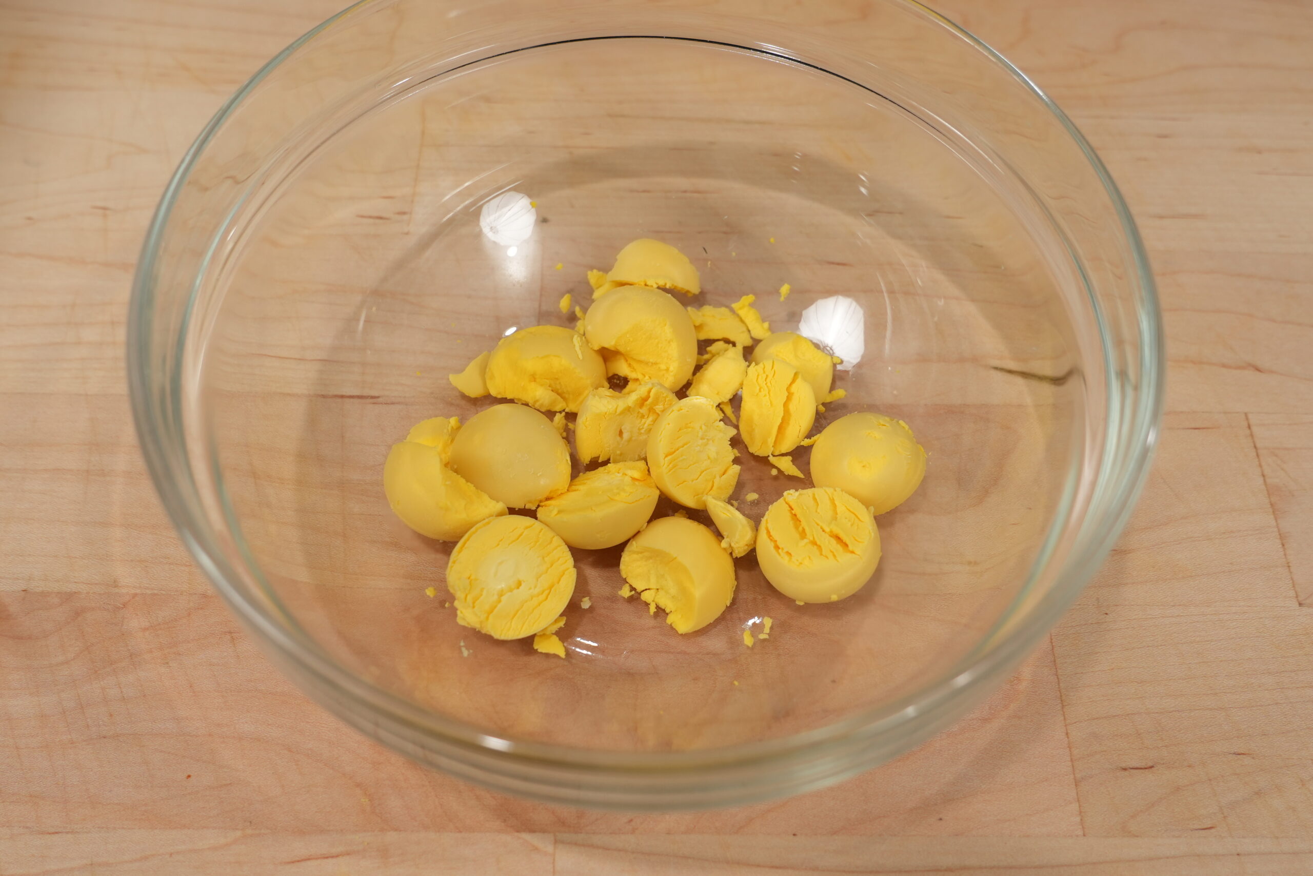 Cooked egg yolks in a glass bowl before mashing