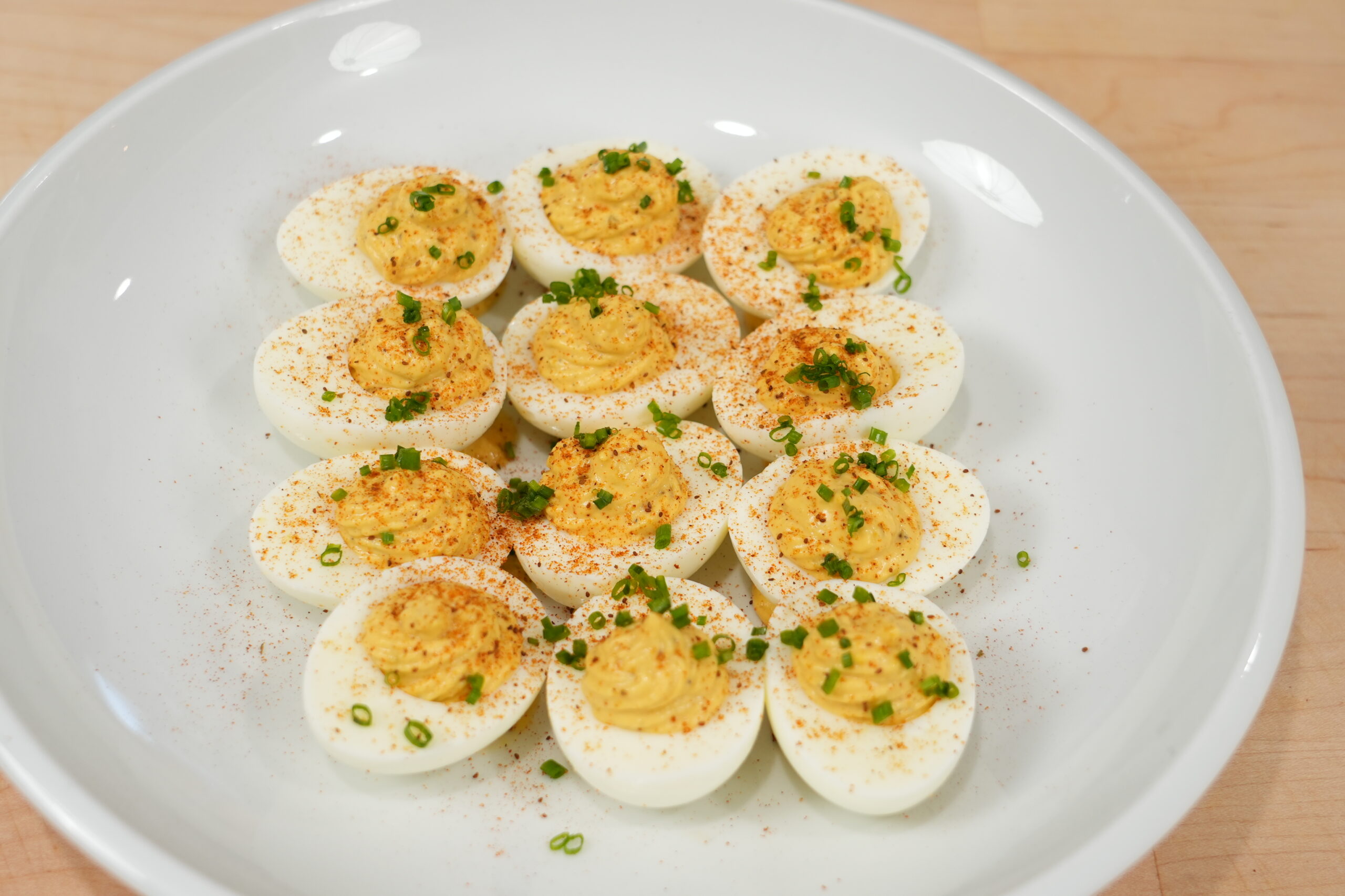 Classic deviled eggs with paprika on a white serving plate