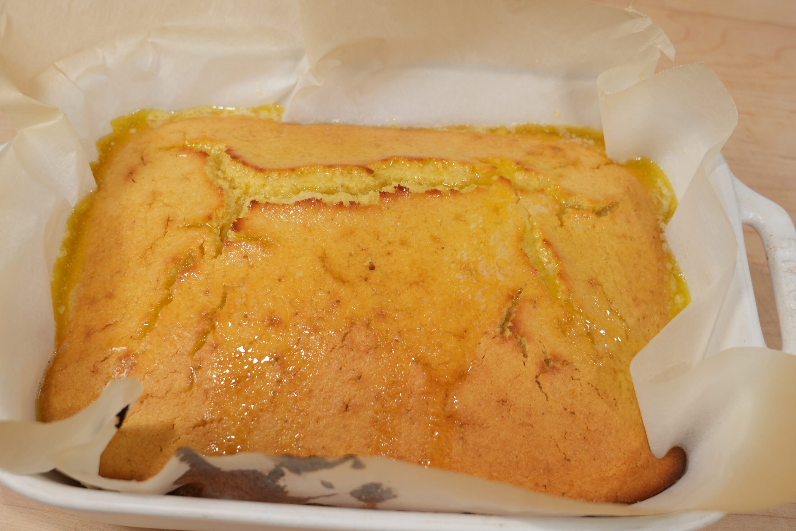 Golden cornbread in a square baking pan, brushed with honey butter
