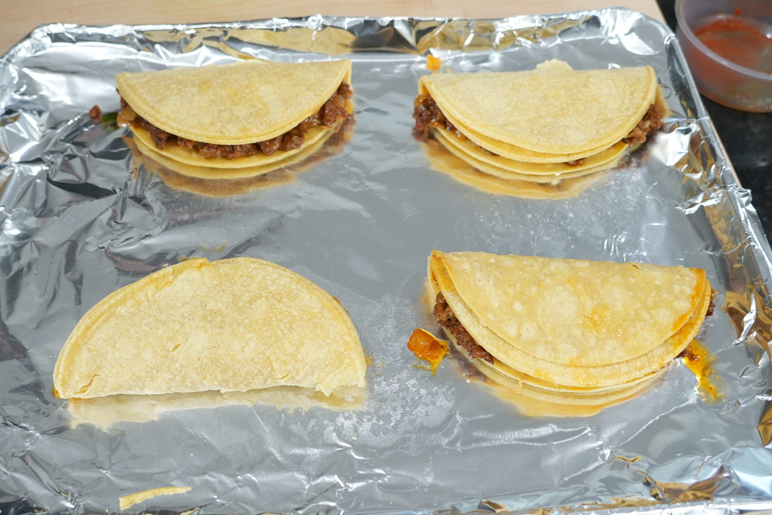 Seasoned beef and cheese folded into doubled corn tortillas before frying