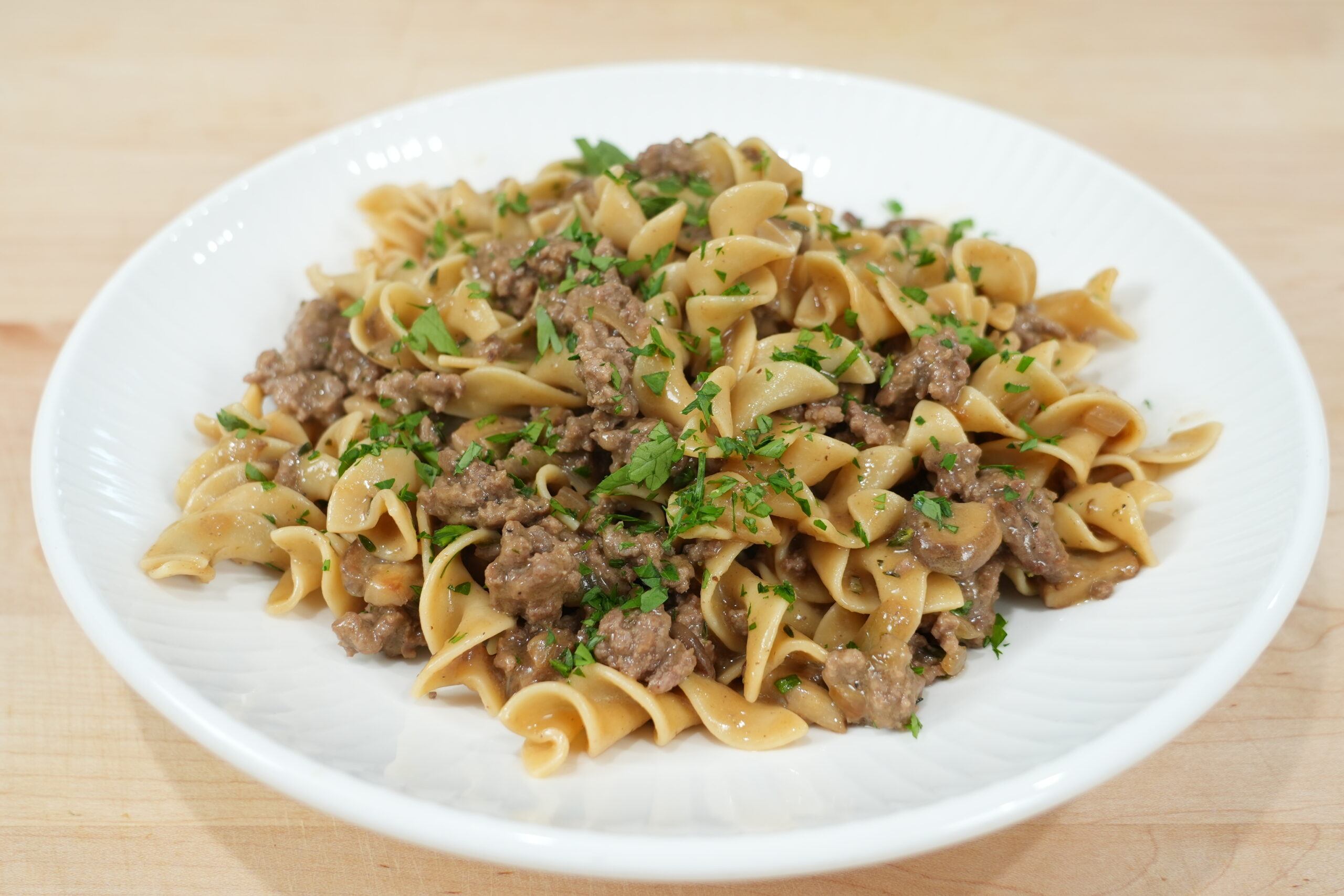 Ground beef stroganoff with mushrooms and egg noodles on a white plate