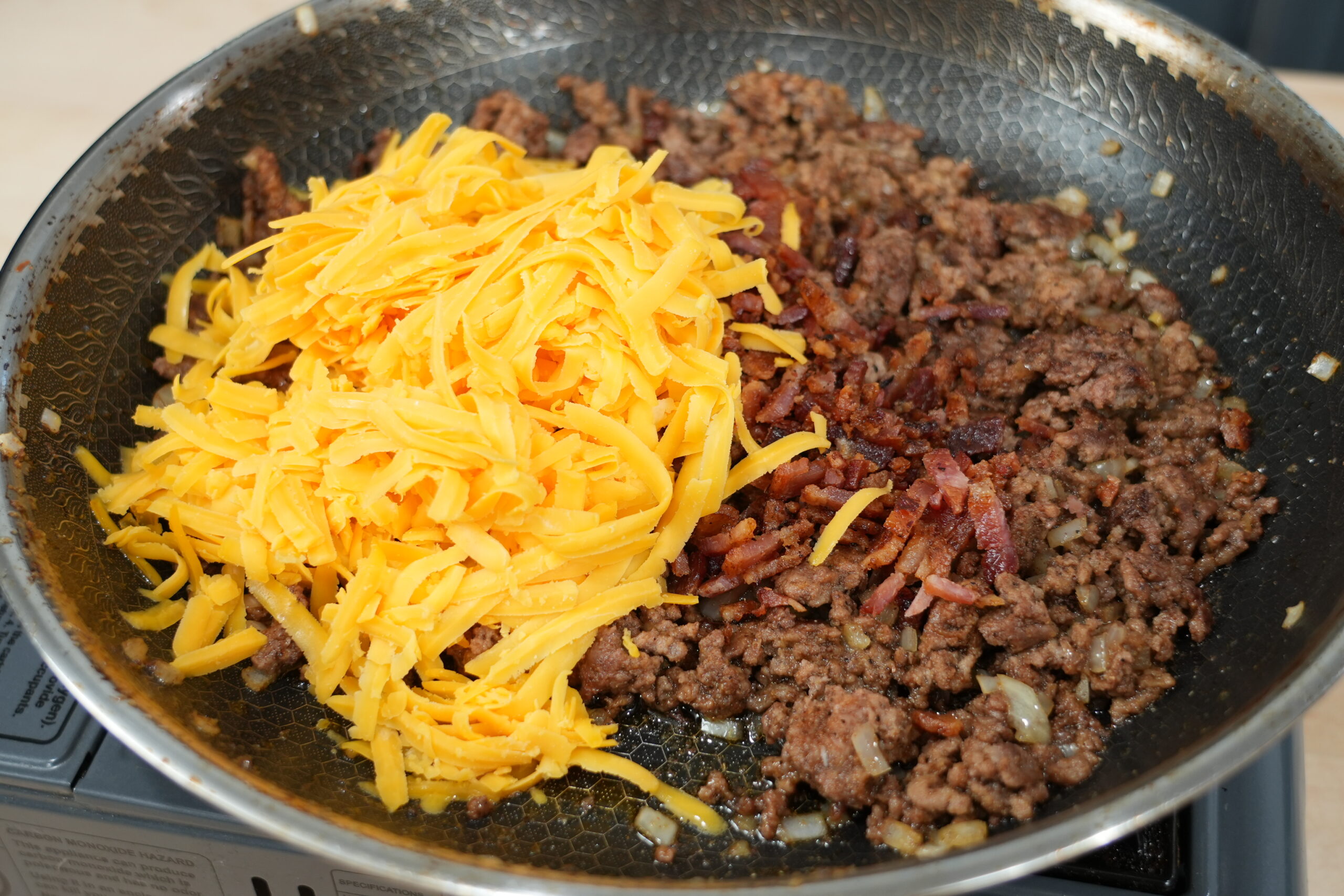 Cooked beef and bacon with shredded cheddar for cheeseburger egg roll filling