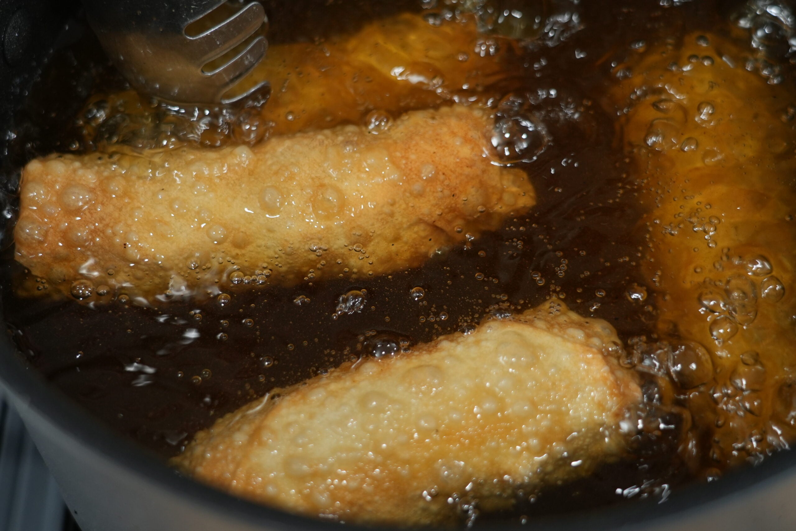 Cheeseburger egg rolls frying until golden and crisp