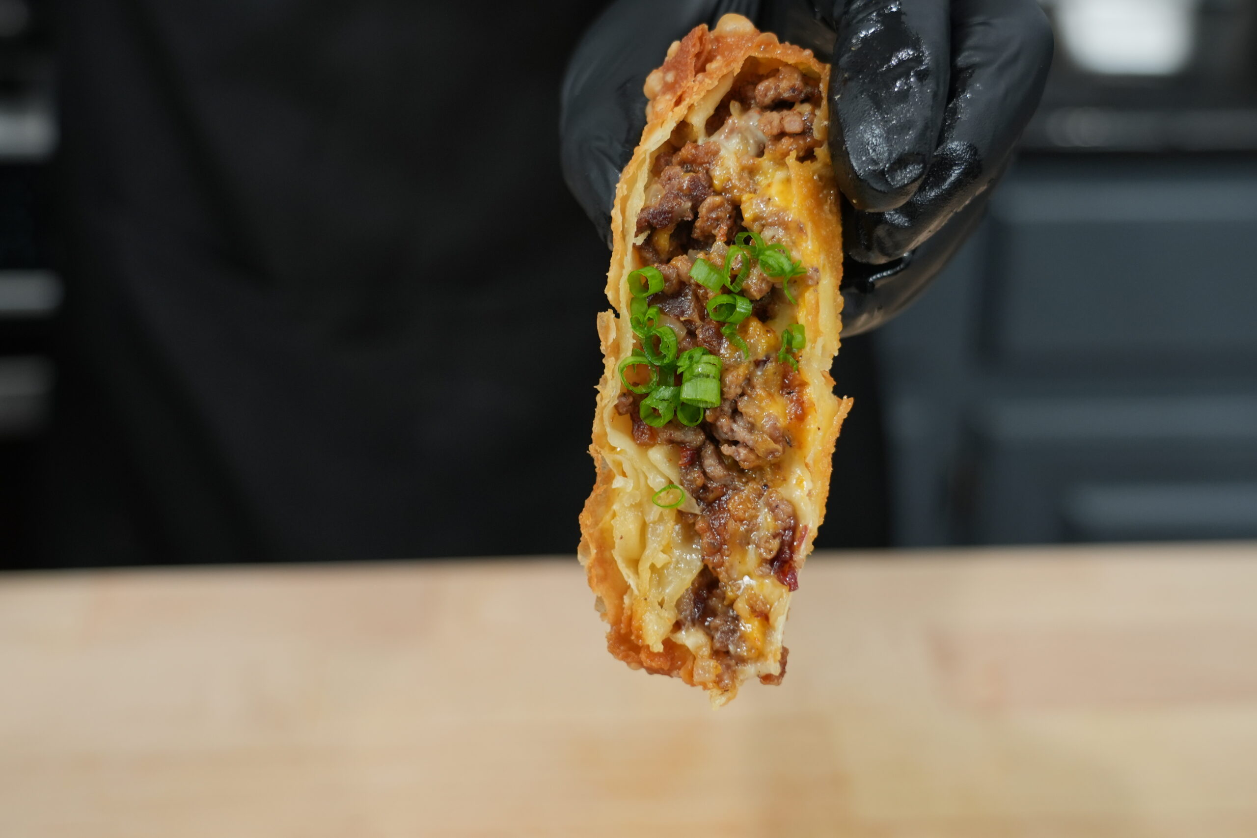 Crispy bacon cheeseburger egg rolls cut open to show the beef and cheese filling