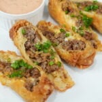 Finished bacon cheeseburger egg rolls cut open with burger sauce