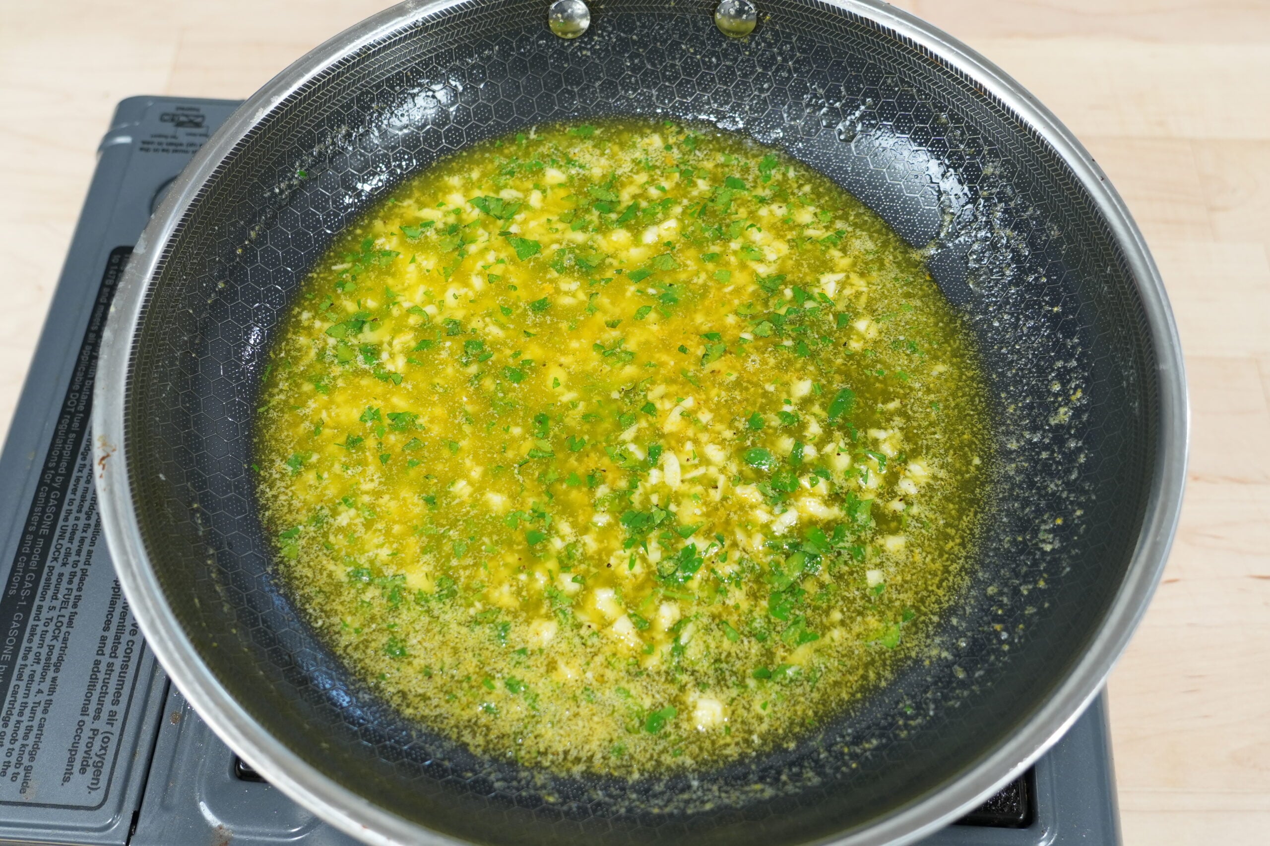 Garlic butter with herbs in a skillet for brushing baked knots