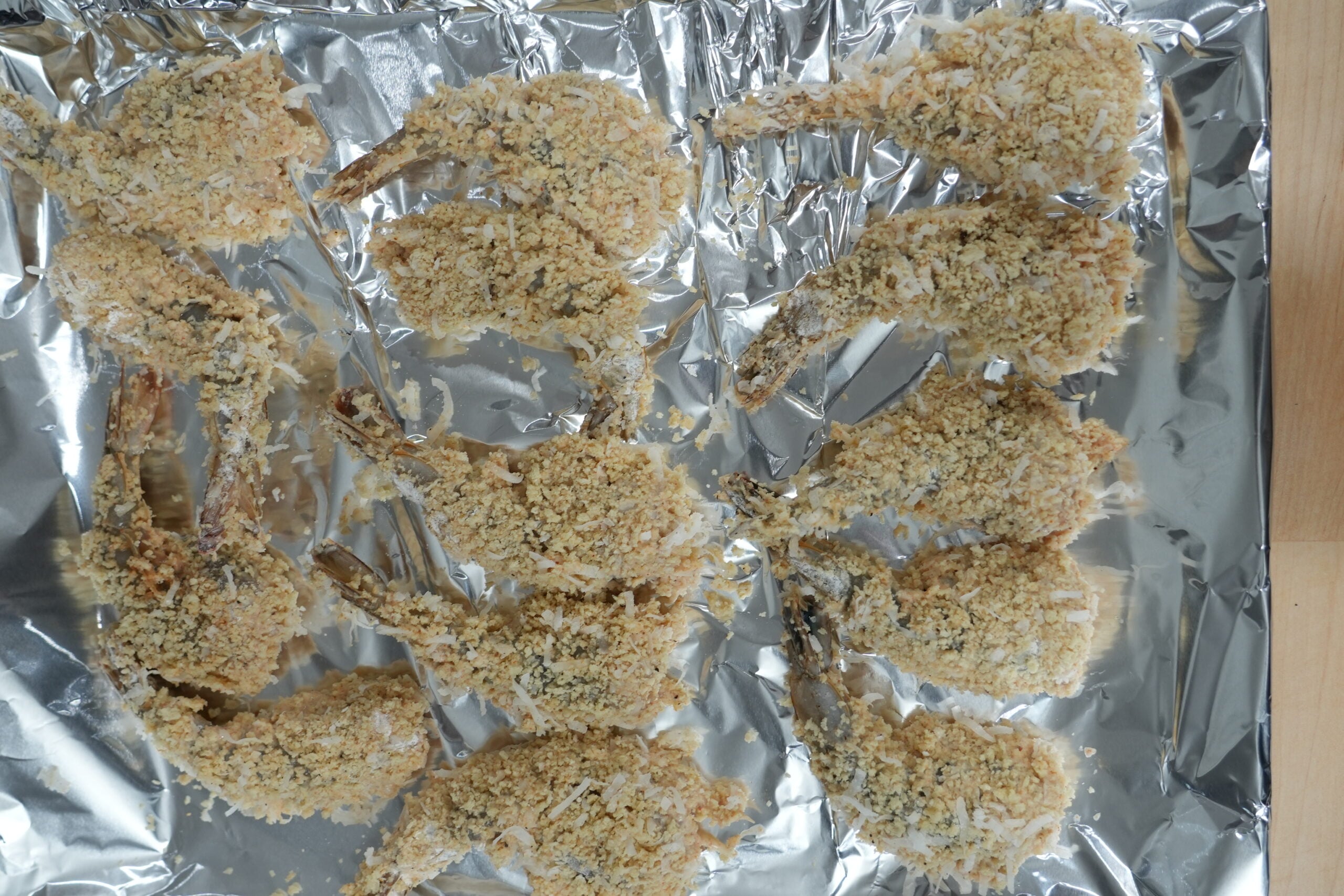 Shrimp coated with panko and coconut on a tray before frying