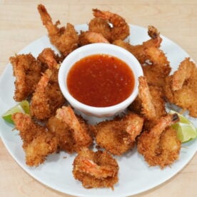 Crispy coconut shrimp with sweet chili dipping sauce and lime wedges