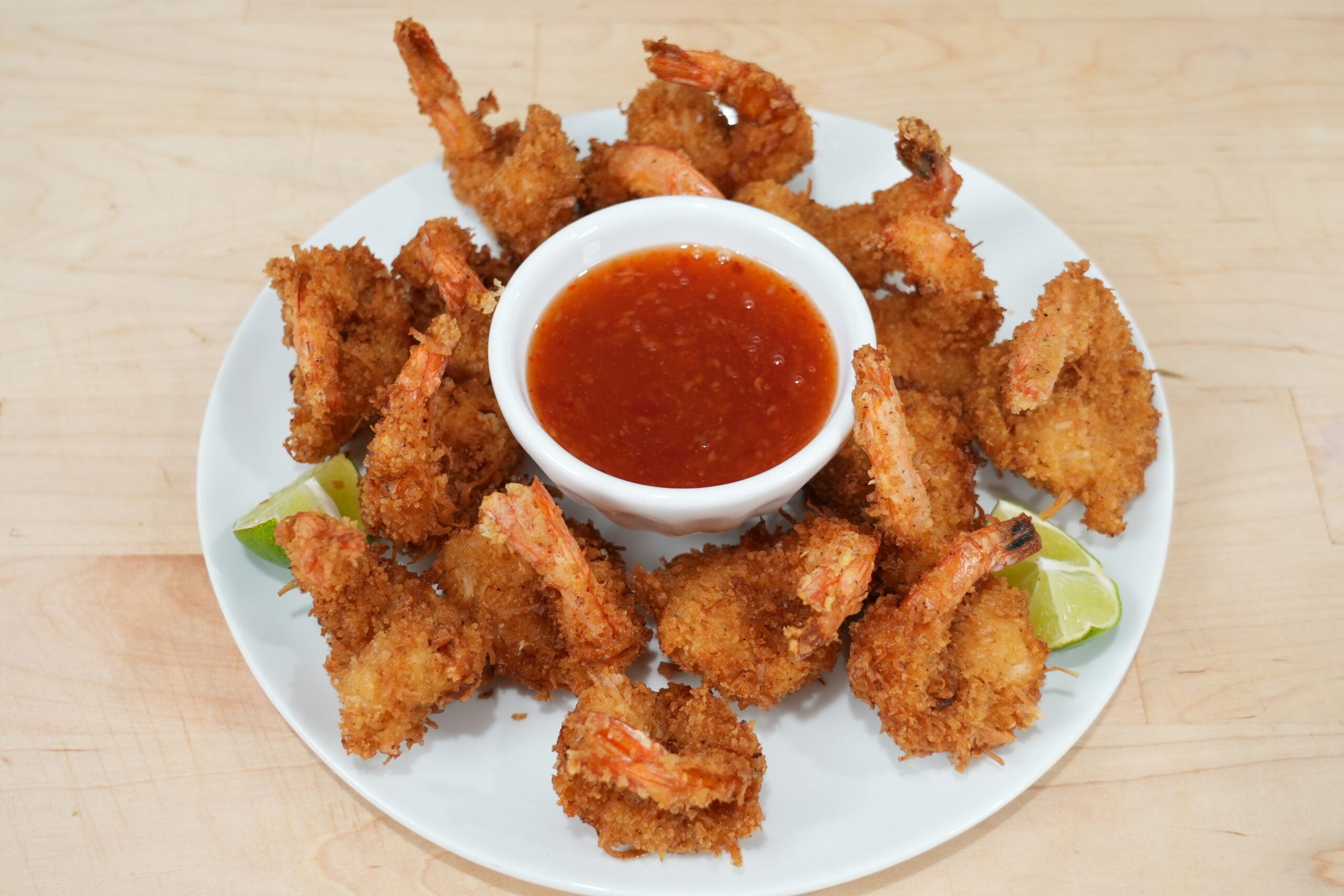 Crispy coconut shrimp with sweet chili dipping sauce and lime wedges