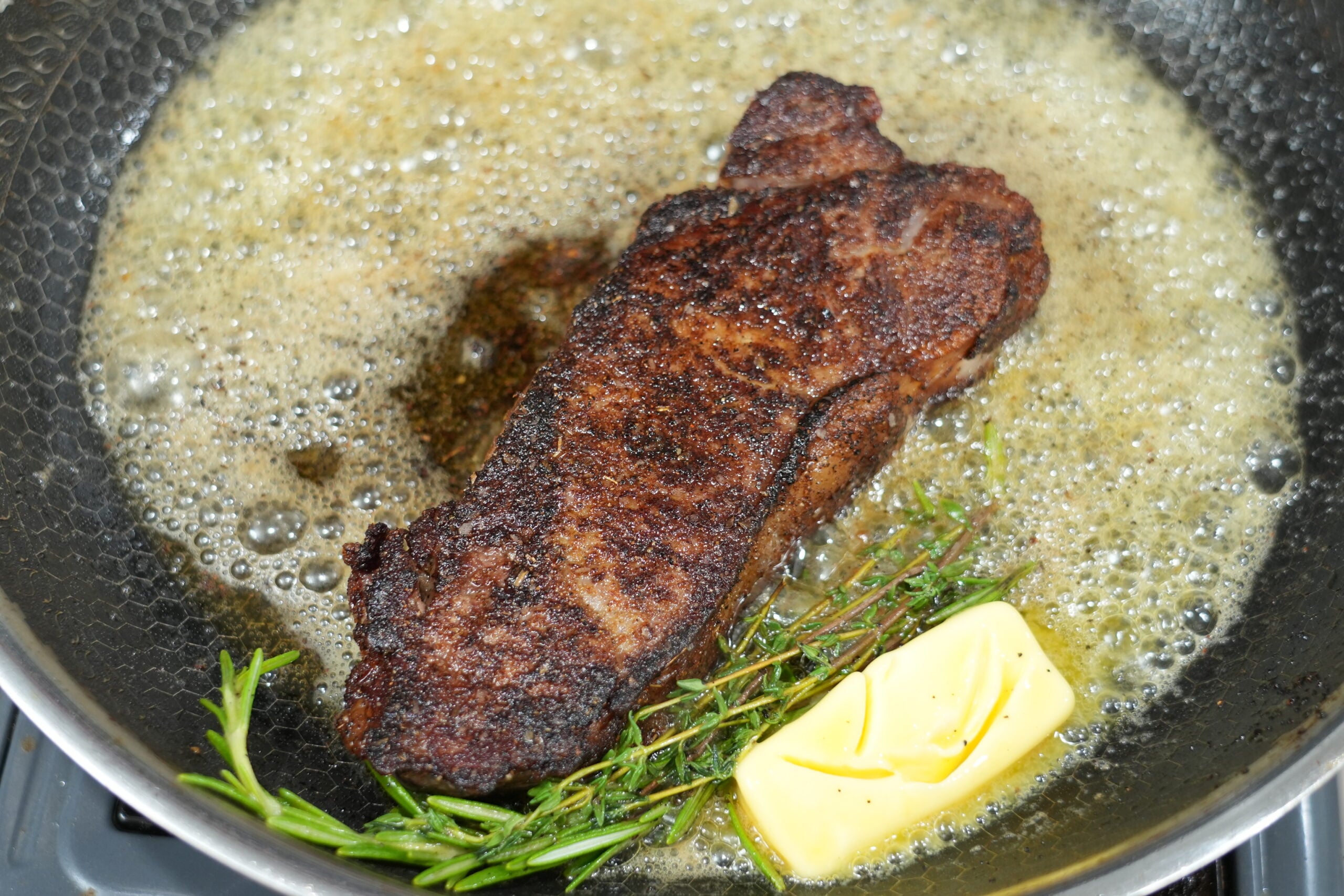 New York strip steak basting in butter with rosemary and thyme