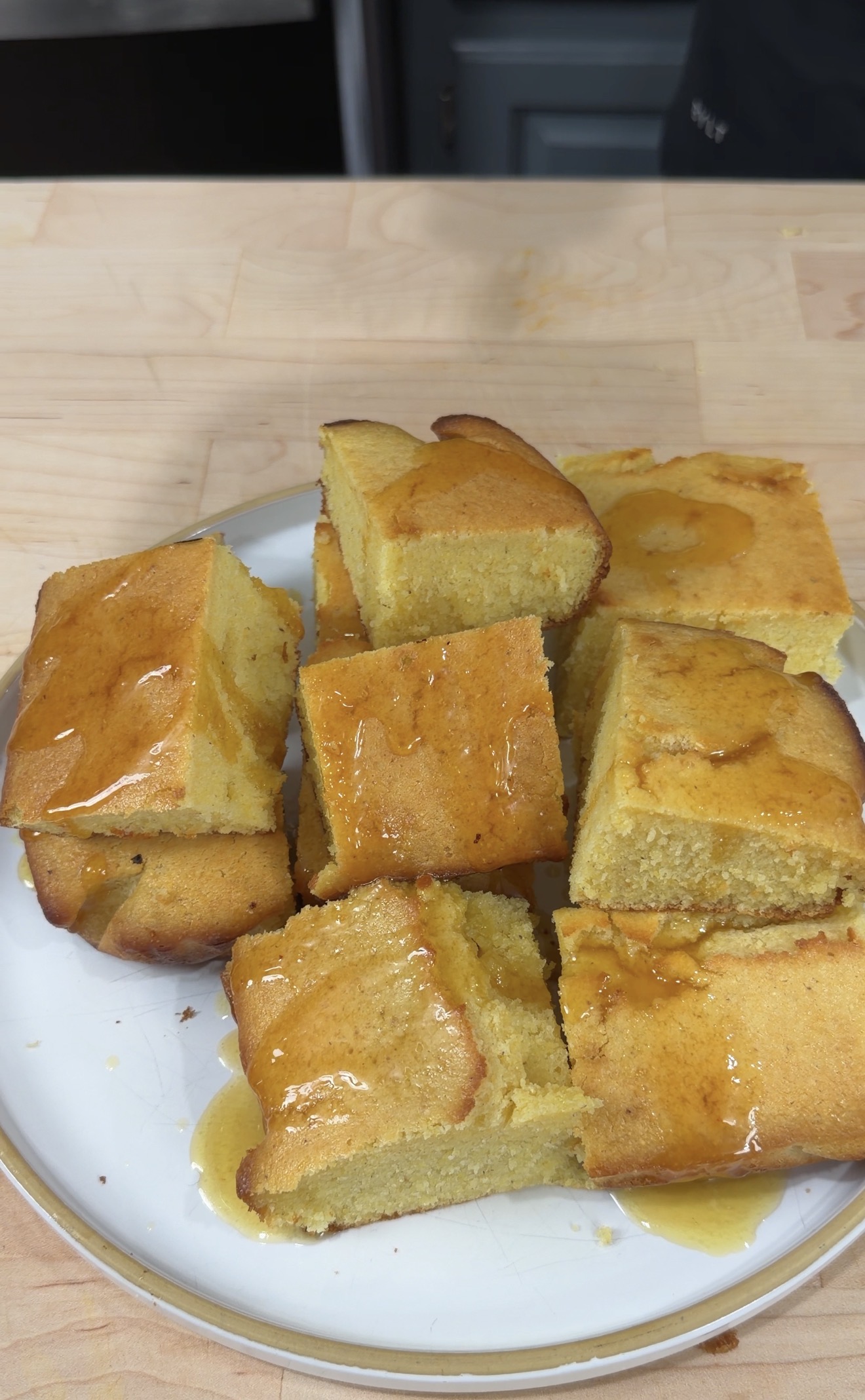 Slices of golden cornbread brushed with honey butter on a white plate